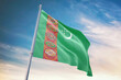 Waving flag of Turkmenistan in blue sky. Turkmenistan flag for independence day. The symbol of the state on wavy fabric.