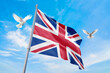 Waving flag of United Kingdom in beautiful sky and flying pigeons. United Kingdom flag for independence day. The symbol of the state on wavy fabric.
