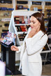 © LIGHTFIELD STUDIOS - appealing stylish woman with long hair in business casual choosing new make up in cosmetics store