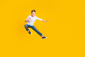 Full length photo of funky positive kid dressed white shirt practicing karate jumping high empty space isolated yellow color background