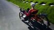 © Robert Peak - Elderly senior woman riding recumbent tricycle e-bike on a path on a sunny day in a park.