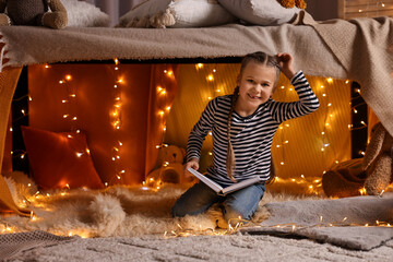 Poster - Girl reading book in decorated play tent at home