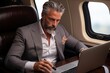 Stylish mature businessman in suit working on tablet during flight on business travel