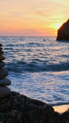 Wall Mural - Concept of balance and harmony. Stack of stones pebbles cairn on the beach coast of the sea in the nature on sunset. Meditative art of stone stacking. Camera pan