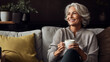 Elderly woman drinks coffee. Experienced girl is resting while sitting on sofa. Elderly man with snow-white smile. Grandmother enjoying homely atmosphere