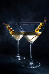 Martini. Two glasses of dirty martini cocktails with vermouth and olives, side view with copy space