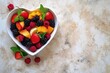 Top view on a heart shaped bowl with a fruit salad and copy space.