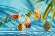 Summer bright alcoholic and non-alcoholic fruit cocktails on a blue background with shadow from palm leaves, sunlight. Summer background, holiday concept, delicious drinks