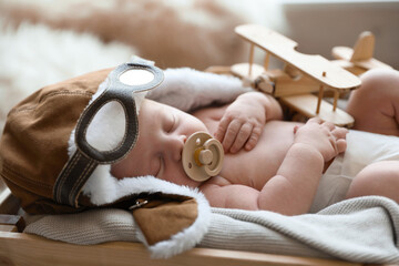 Canvas Print - Cute newborn baby wearing aviator hat with toy sleeping in wooden crate