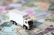 Delivery truck on many banknotes of different currency. Background of trucking or moving concept close up
