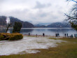 Lungo il Lago di Bled con cielo nuvoloso neve e turisti a passeggio