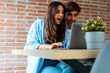 © simona - Excited couple make winner expression in front of an open laptop after win money. Successful moment at home with young man and woman watching computer together. Surprise and happiness online business