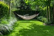 young green mown grass, green bushes, ornamental grass and a hammock in the background