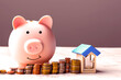 Ein rosa Sparschwein mit Türmen aus Münzen daneben und einem Haus, Hausbau Finanzierung