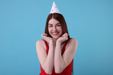 Poster - Happy woman in party hat on light blue background