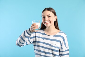 Poster - Happy woman with milk mustache holding glass of tasty dairy drink on light blue background