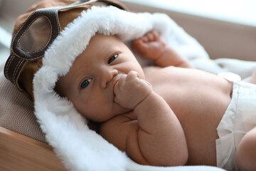 Wall Mural - Cute newborn baby in aviator hat lying on blanket, closeup