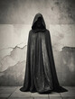 figure draped in black cloak and worn wall