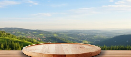 Canvas Print - A wooden table with a cutting board on it placed in a natural landscape with a mountain in the background, surrounded by grass, trees and a serene lake under a cloudy sky