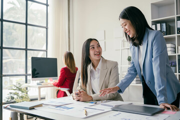 Wall Mural - Three women are sitting at a desk, one of them is smiling