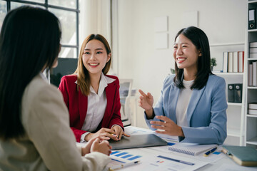 Wall Mural - Three women are sitting at a table, smiling and talking to each other