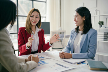 Wall Mural - Three women are sitting at a table, smiling and talking to each other