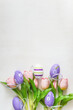 Easter holiday celebration banner; greeting card concept: Bouquet of pink tulips and easter eggs on a white paint wooden background