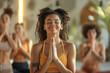 Group yoga and meditation class promotes fitness and relaxation, A woman in a yellow tank top is praying in a yoga class. The other people in the class are also praying