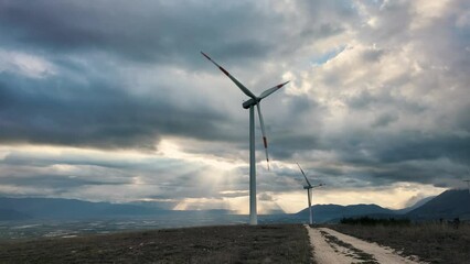 Wall Mural - 4k video of Wind farm or wind park at sunset located in the mountains of Italy Europe to realize clean energy. Sustainable, renewable energy for enviromental.