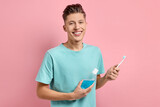 Fototapeta Tulipany - Young man with mouthwash and toothbrush on pink background