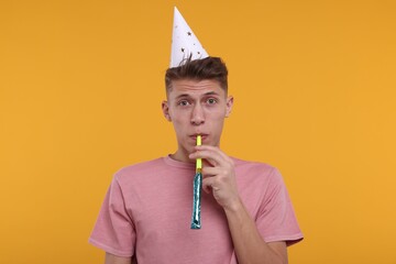 Poster - Young man in party hat with blower on orange background