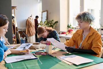 Inclusive group of girls drawing clothing sketches in tailoring class at table