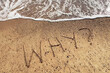 LARGE capital letters text WHY on the sand of the beach and water waves. Top view.