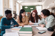 © Mediaphotos - Multiethnic group of students discussing project sitting at table in college library with young Asian woman speaking