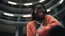 Joyful millennial female with vitiligo skin beautifully smiling at camera while enjoying online music in headphones. Portrait of African American young woman listen playlist in earbuds. Slow motion
