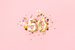 Gold colored number 50 and stars confetti on a pink background. Creative concept.