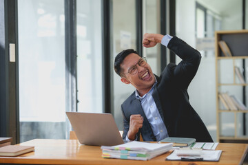 Wall Mural - A man in a suit is celebrating with his hands raised in the air