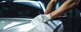 Fototapeta Londyn - Close-up of a man's hand using a white microfiber cloth to polish a shiny white car