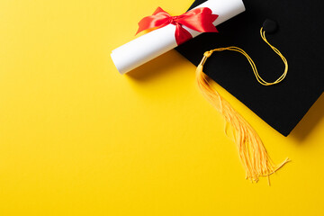 Wall Mural - Flat lay composition with graduation cap and diploma on yellow background.