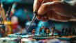 A close-up of an artist's hand carefully painting miniature figures, surrounded by a colorful and artistic workspace