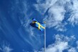 Swedish Flag on Blue Summer Sky Background. Symbol of Nation and Country
