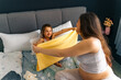© DusanJelicic - Mother and daughter are folding together a sleeping blanket for the baby, sitting on the bed and smiling