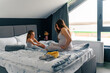 © DusanJelicic - Mother and daughter are sitting on the bed in front of the window and talking about what they are going to do that day