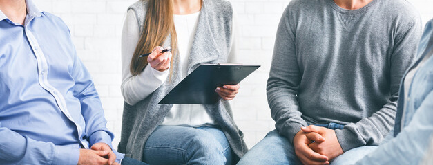 Psychotherapist talking with patients during group therapy session and taking notes