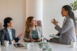© lordn - A diverse group of multi-ethnic businesswomen sit in the office and have a conversation. They engage in discussions, reflecting their entrepreneurial spirit and collaboration