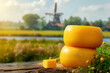 Wheels of Dutch cheese, with canals and windmill in Holland in the background