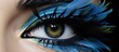 A closeup of a human body organ, the eye, with azure feathers painted on the eyelashes. The art piece showcases electric blue eye shadow blending into the darkness of the iris