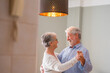 © Daniel - Joyful active old retired romantic couple dancing laughing in living room, happy middle aged wife and elder husband having fun at home, smiling senior family grandparents relaxing bonding together.