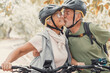 © Daniel - Couple of cute and sweet seniors in love enjoying together nature outdoors having fun with bikes. Old man kissing his wife smiling and feeling good..