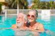 © Daniel - Couple of two happy seniors having fun and enjoying together in the swimming pool smiling and playing. Happy people enjoying summer outdoor in the water.